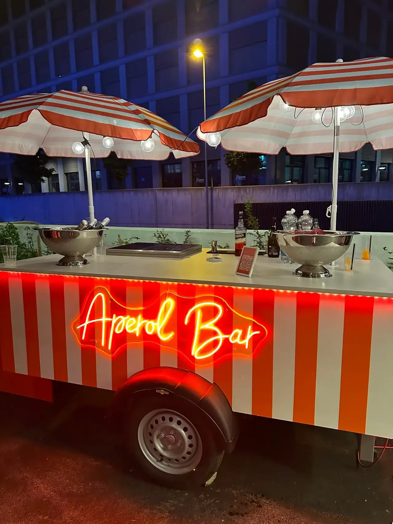Delpuffo Bar am Abend mit leuchtender Neonschrift Aperol Bar